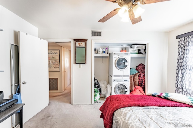 carpeted bedroom featuring stacked washer / drying machine, a closet, visible vents, and a ceiling fan