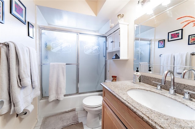 full bathroom with combined bath / shower with glass door, toilet, vanity, and tile patterned floors