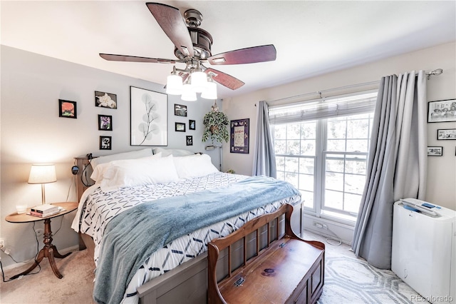 bedroom featuring a ceiling fan, light colored carpet, and multiple windows