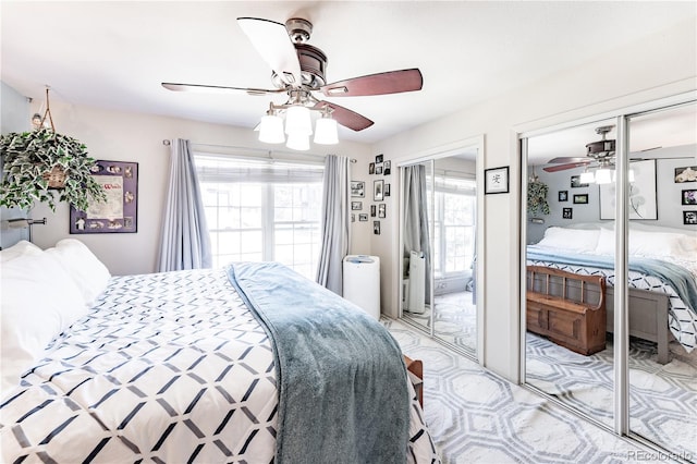 bedroom with two closets, ceiling fan, and multiple windows