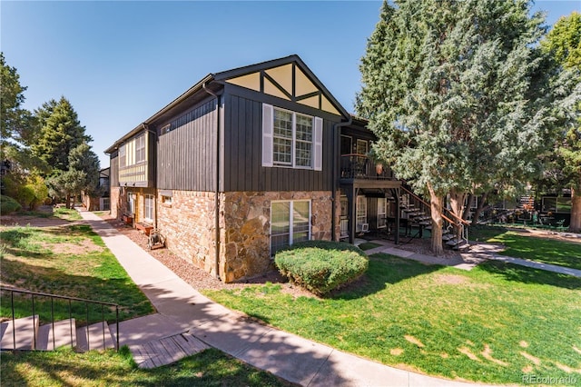 view of home's exterior featuring stone siding, stairway, a yard, and a deck