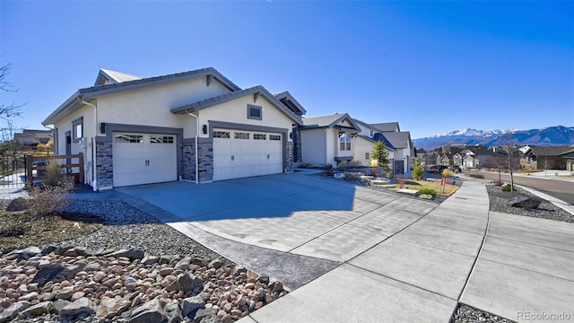 view of front of property with stucco siding, concrete driveway, a mountain view, a garage, and stone siding