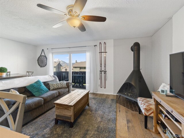 1263 Straight Creek Dr Unit 205, Dillon, CO 80435 - living area featuring wood finished floors, a textured ceiling, a ceiling fan, and a wood stove