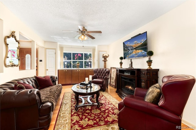 5215 S Washington St, Littleton, CO 80121 - living room featuring wood finished floors, a textured ceiling, a ceiling fan, and a glass covered fireplace