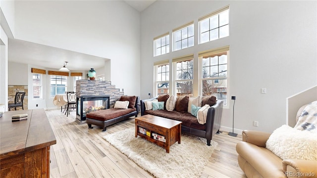 living room featuring a fireplace, light hardwood / wood-style floors, and a high ceiling