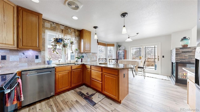 kitchen featuring dishwasher, sink, black electric range oven, hanging light fixtures, and kitchen peninsula