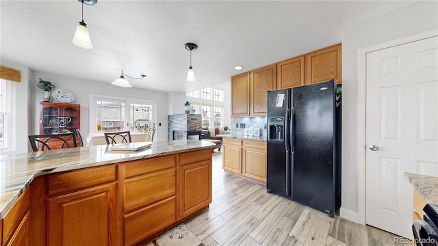 kitchen featuring black fridge, decorative light fixtures, range, light hardwood / wood-style floors, and backsplash