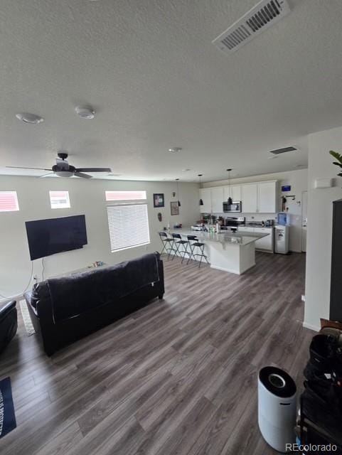 18006 E 103rd Ave, Commerce City, CO 80022 - living area featuring a textured ceiling, ceiling fan, and dark wood finished floors