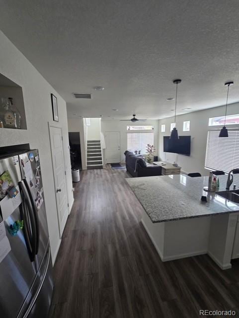 18006 E 103rd Ave, Commerce City, CO 80022 - kitchen with freestanding refrigerator, dark wood finished floors, pendant lighting, light stone countertops, and open floor plan