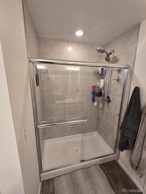 18006 E 103rd Ave, Commerce City, CO 80022 - bathroom with a stall shower, wood finished floors, and a textured ceiling