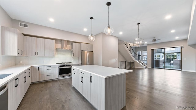 kitchen featuring a center island, appliances with stainless steel finishes, pendant lighting, backsplash, and wall chimney exhaust hood