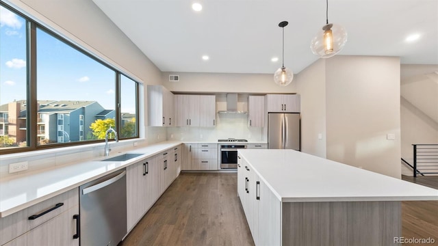 kitchen featuring pendant lighting, sink, a center island, wall chimney range hood, and stainless steel appliances