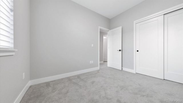 unfurnished bedroom with light colored carpet and a closet