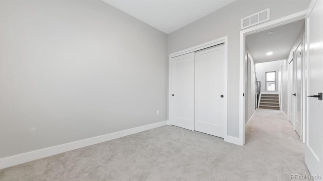 unfurnished bedroom featuring light colored carpet and a closet