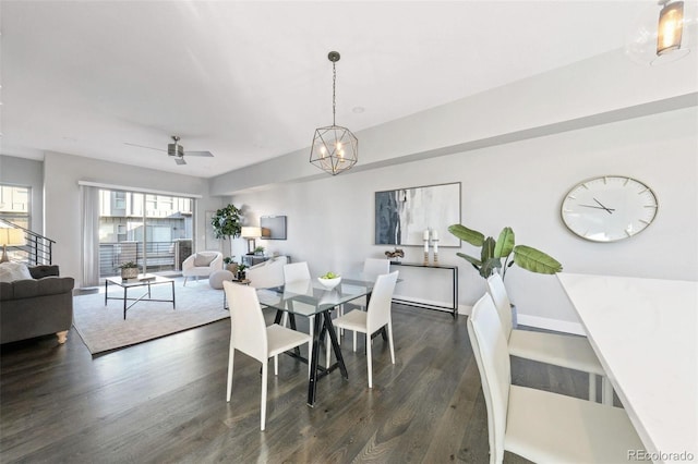 dining area with ceiling fan with notable chandelier and dark hardwood / wood-style floors