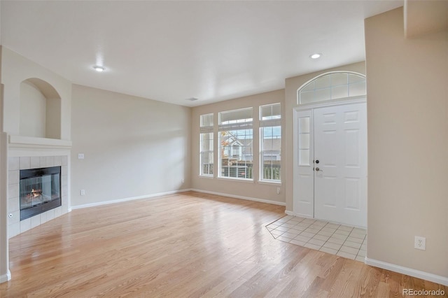 entryway featuring a tiled fireplace and light hardwood / wood-style flooring