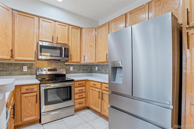 kitchen with light tile patterned flooring, light brown cabinetry, appliances with stainless steel finishes, and tasteful backsplash