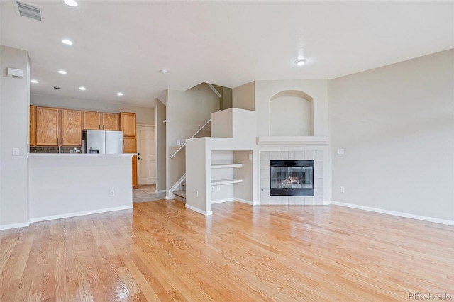 unfurnished living room featuring a tile fireplace and light hardwood / wood-style flooring