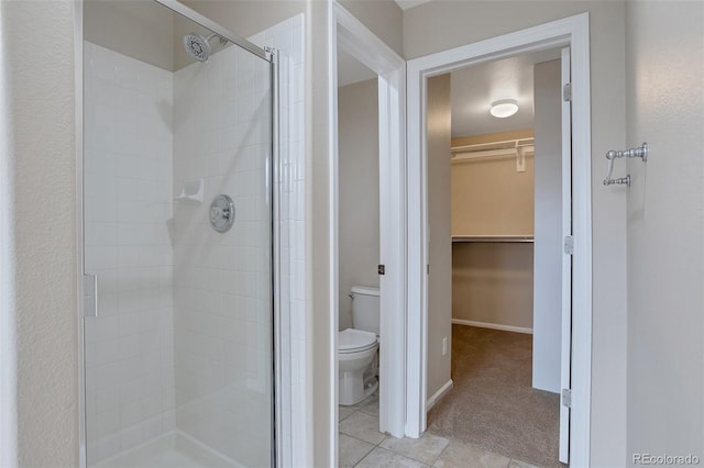 bathroom featuring tile patterned floors, toilet, and a shower with door