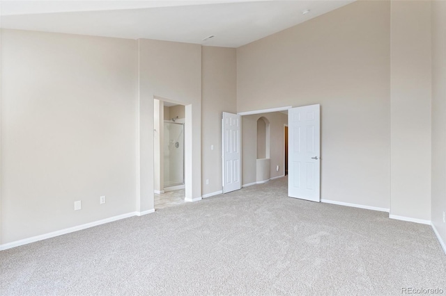 spare room featuring light colored carpet and a high ceiling