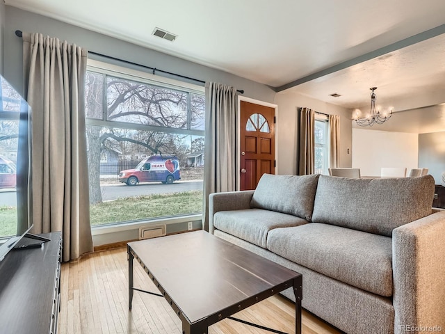 living room featuring plenty of natural light, a notable chandelier, and light hardwood / wood-style floors