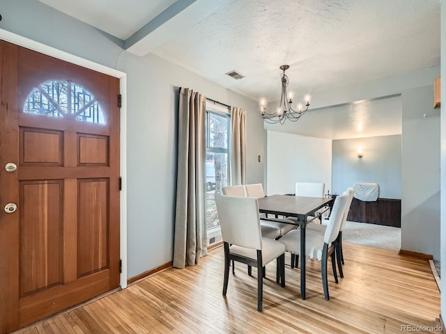 dining room featuring a textured ceiling, a chandelier, and light hardwood / wood-style flooring