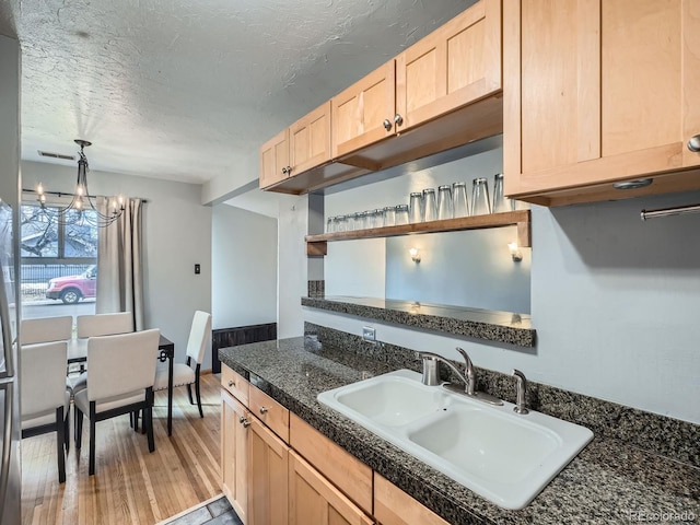 kitchen featuring sink, light wood-type flooring, a chandelier, light brown cabinets, and a textured ceiling