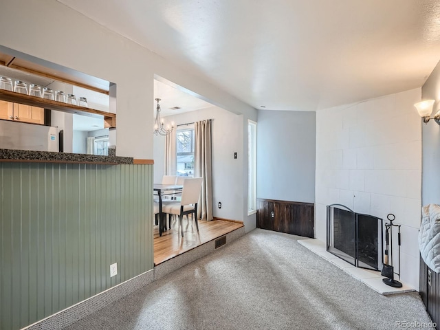 unfurnished living room with a large fireplace, light carpet, and an inviting chandelier