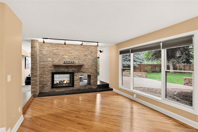 6338 S Oneida Ct, Centennial, CO 80111 - unfurnished living room with track lighting, wood finished floors, and a stone fireplace