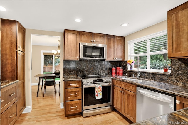 6338 S Oneida Ct, Centennial, CO 80111 - kitchen with appliances with stainless steel finishes, dark stone countertops, light wood finished floors, a chandelier, and recessed lighting