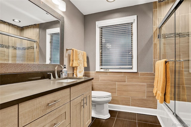 6338 S Oneida Ct, Centennial, CO 80111 - full bathroom featuring vanity, tile walls, bath / shower combo with glass door, a textured wall, and recessed lighting
