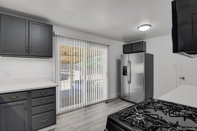 8381 Vine St, Denver, CO 80229 - kitchen featuring stainless steel fridge, black range with gas cooktop, light wood finished floors, light countertops, and gray cabinetry