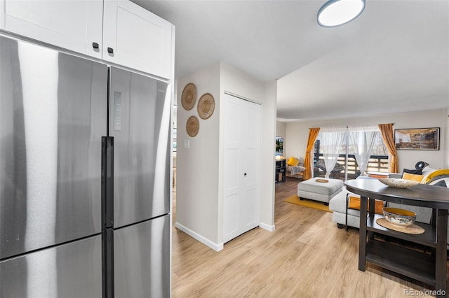 495 S Dayton St Unit 1C, Denver, CO 80247 - kitchen with baseboards, stainless steel refrigerator, open floor plan, white cabinets, and light wood finished floors