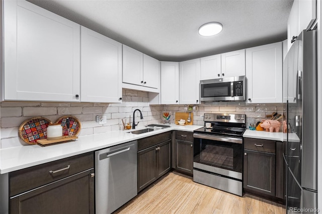 495 S Dayton St Unit 1C, Denver, CO 80247 - kitchen featuring dark brown cabinetry, appliances with stainless steel finishes, light countertops, a sink, and backsplash