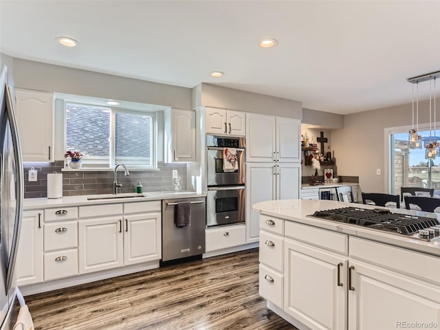 8862 Chestnut Hill Ln, Highlands Ranch, CO 80130 - kitchen featuring appliances with stainless steel finishes, a sink, tasteful backsplash, wood finished floors, and white cabinets