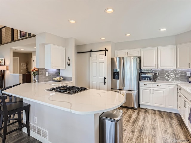 8862 Chestnut Hill Ln, Highlands Ranch, CO 80130 - kitchen featuring appliances with stainless steel finishes, light wood-style floors, light stone countertops, a barn door, and recessed lighting