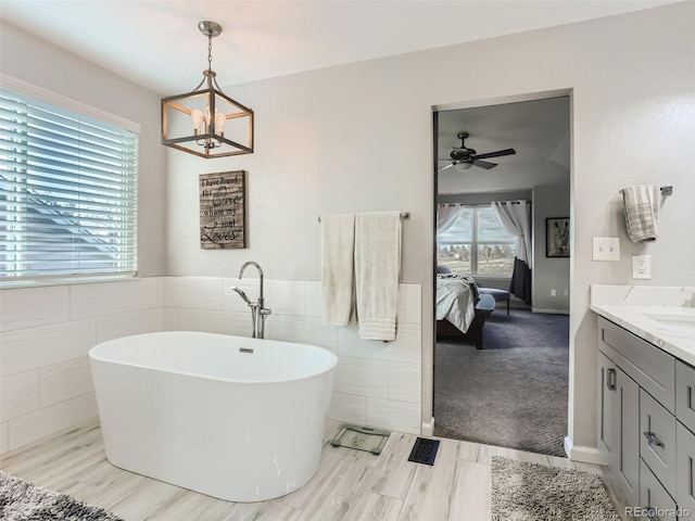 8862 Chestnut Hill Ln, Highlands Ranch, CO 80130 - bathroom featuring tile walls, ensuite bath, a freestanding bath, vanity, and a ceiling fan