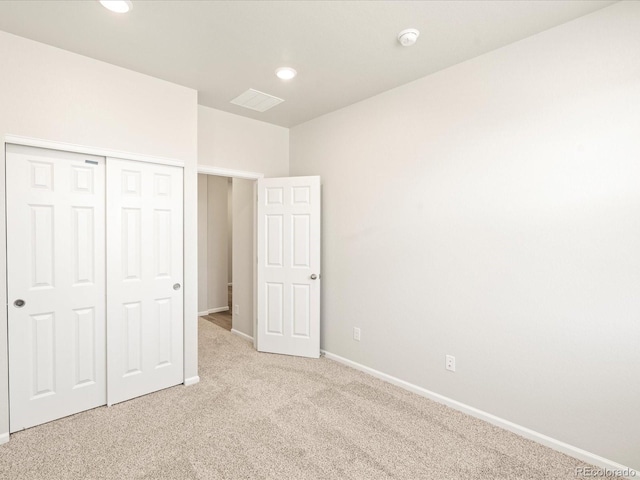 unfurnished bedroom with light carpet and a closet