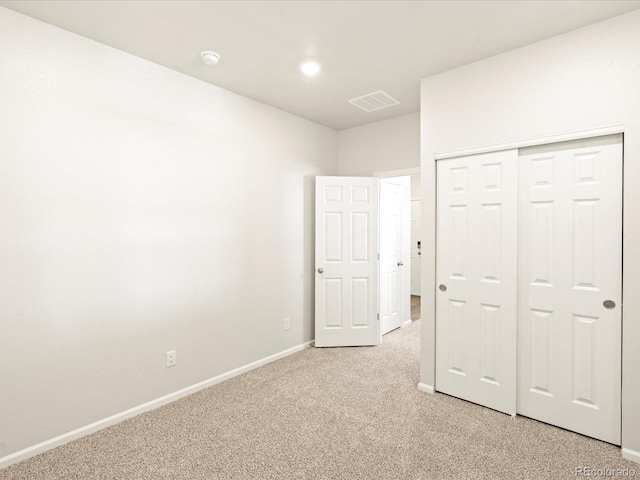 unfurnished bedroom featuring light colored carpet and a closet