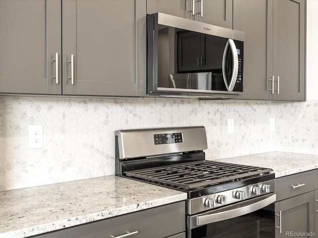 kitchen with gray cabinetry, backsplash, and stainless steel appliances