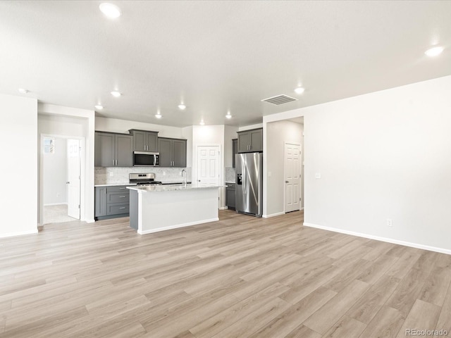 kitchen featuring a kitchen island with sink, gray cabinets, light hardwood / wood-style floors, and appliances with stainless steel finishes