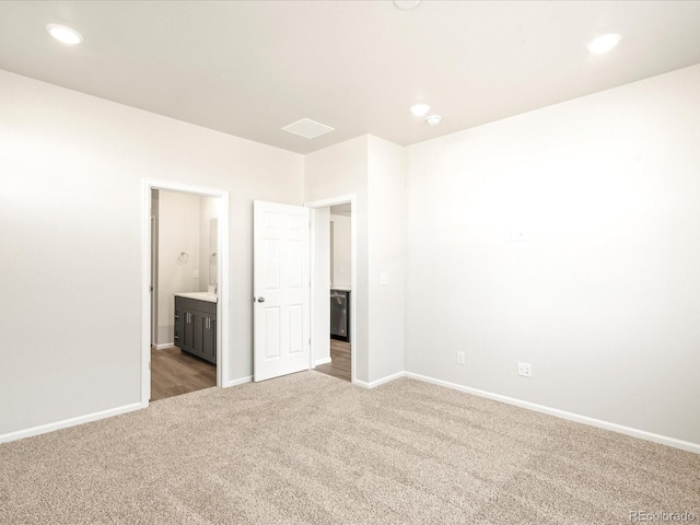 unfurnished bedroom with connected bathroom and carpet floors