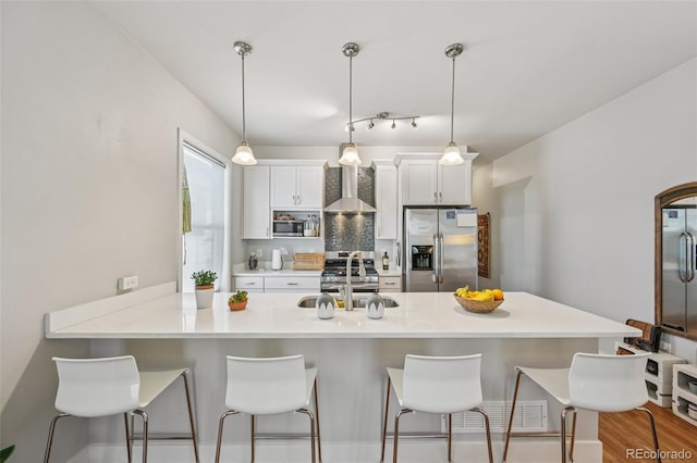 3444 Lawrence St, Denver, CO 80205 - kitchen with stainless steel appliances, a sink, wall chimney exhaust hood, a breakfast bar area, and white cabinets