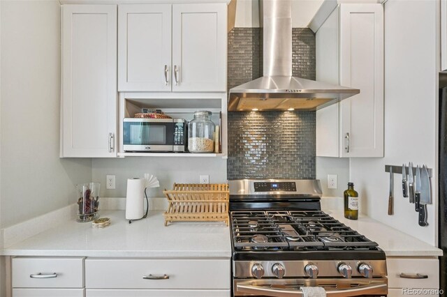 3444 Lawrence St, Denver, CO 80205 - kitchen with wall chimney range hood, appliances with stainless steel finishes, white cabinetry, and backsplash