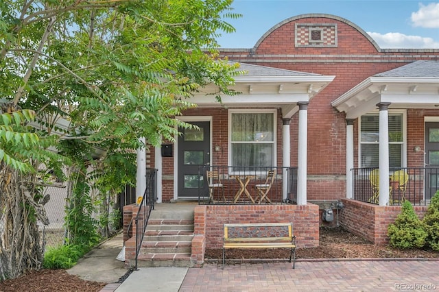 3444 Lawrence St, Denver, CO 80205 - property entrance featuring covered porch, brick siding, and roof with shingles