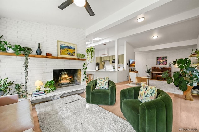 5200 W Rowland Ave, Littleton, CO 80128 - living room featuring ceiling fan, brick wall, a brick fireplace, beam ceiling, and light wood-style floors
