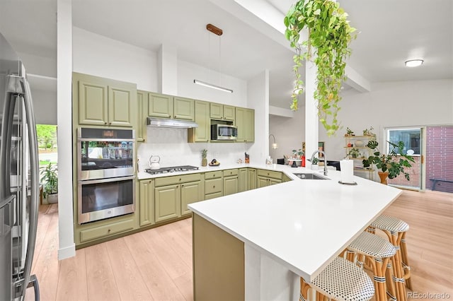 5200 W Rowland Ave, Littleton, CO 80128 - kitchen featuring green cabinetry, a peninsula, stainless steel appliances, a sink, and beam ceiling