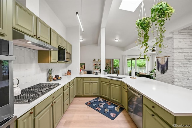 5200 W Rowland Ave, Littleton, CO 80128 - kitchen with green cabinetry, stainless steel appliances, a sink, a peninsula, and light wood-style floors