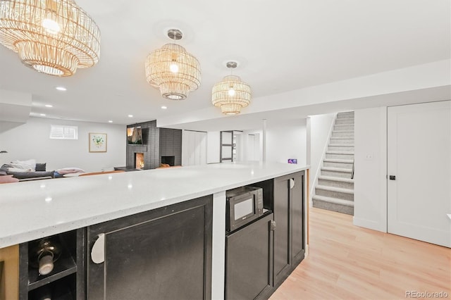 5200 W Rowland Ave, Littleton, CO 80128 - kitchen featuring open floor plan, black microwave, light wood-style floors, a fireplace, and recessed lighting