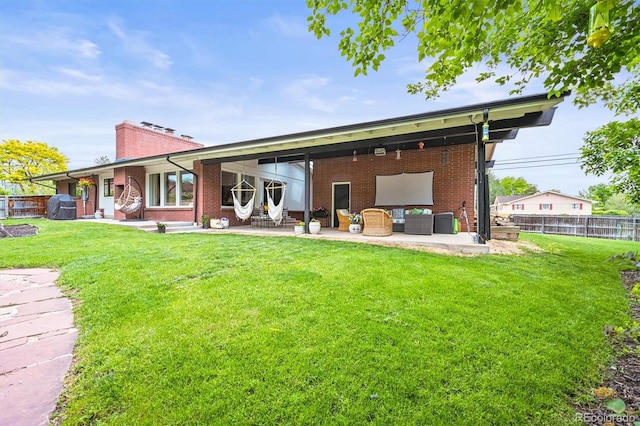 5200 W Rowland Ave, Littleton, CO 80128 - back of property with brick siding, an outdoor living space, a chimney, and a patio area